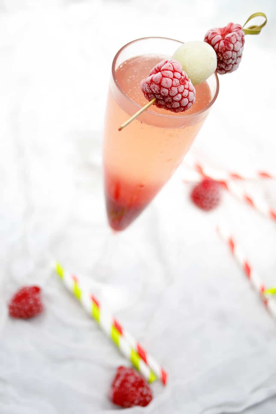 Overhead picture of a raspberry champagne cocktail on white background