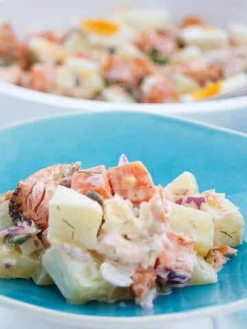 Salmon potato salad on a blue plate, white background