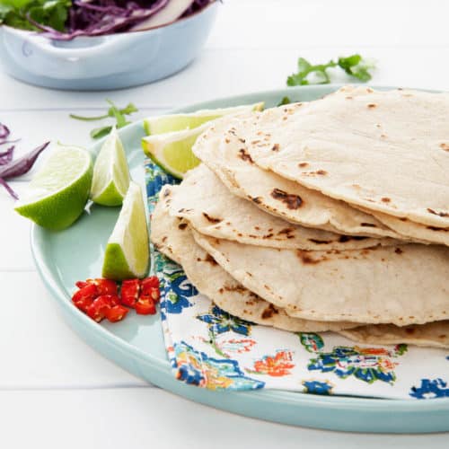 Homemade corn tortilla on blue plate and white background