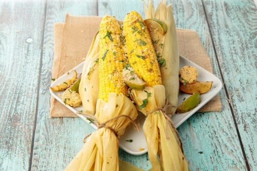 Mexican Street corn with husks on a blue background
