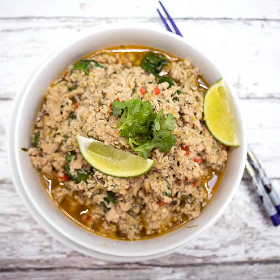 Overhead shot of Thai Pork Larb in a white bowl on wooden background