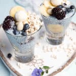 Layered blue chia puding in a glass with berries and banana