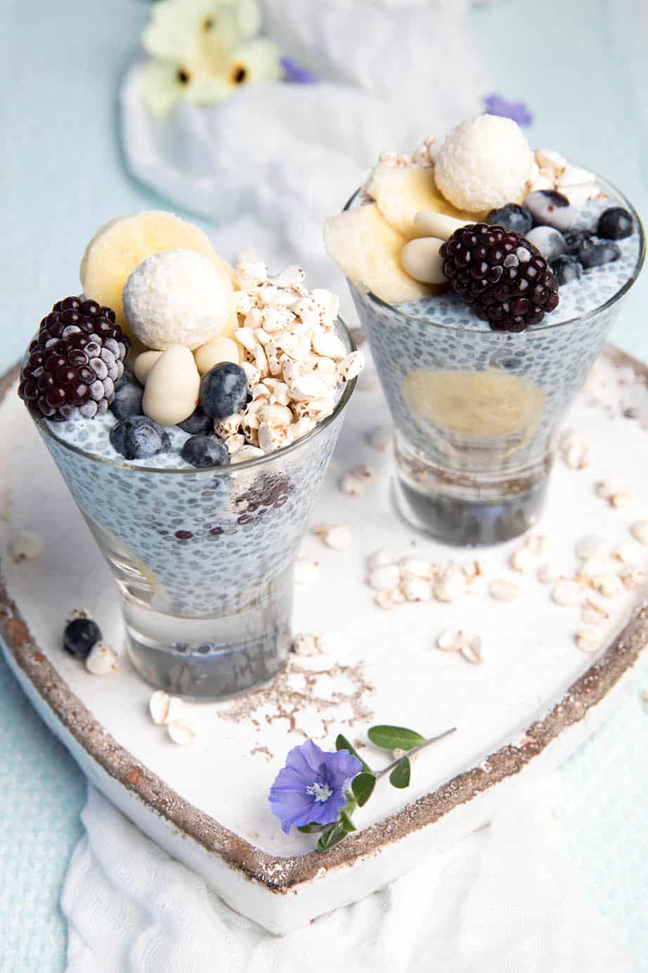Layered blue chia puding in a glass with berries and banana