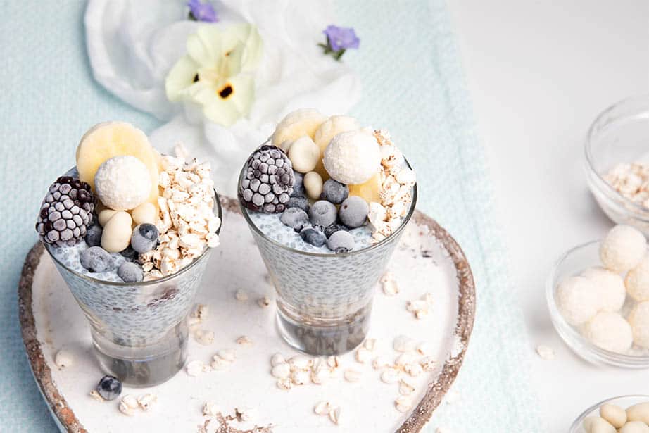 Blue Chia Puddings on a white and light blue background with berries