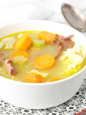 Close up white bowl with corned beef and cabbage soup