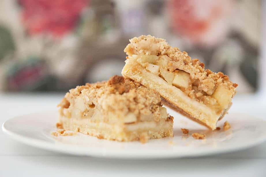 Close up image of apple slice with streusel topping against a coloured background