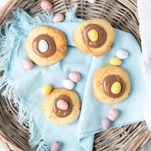 Overhead shot of chocolate thumbprint Easter Cookies in a basket on blue napkin