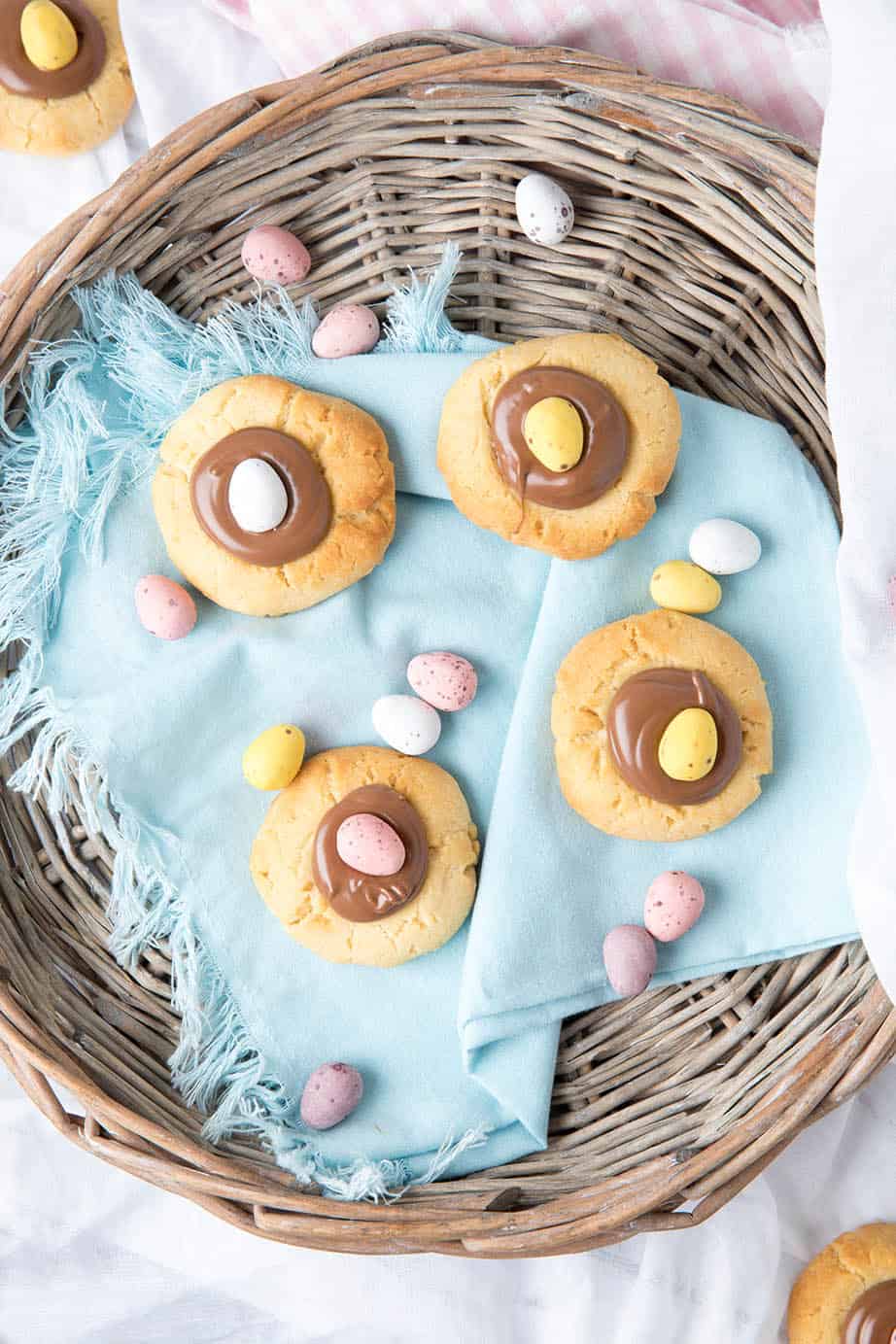 Overhead shot of chocolate thumbprint Easter Cookies in a basket on blue napkin