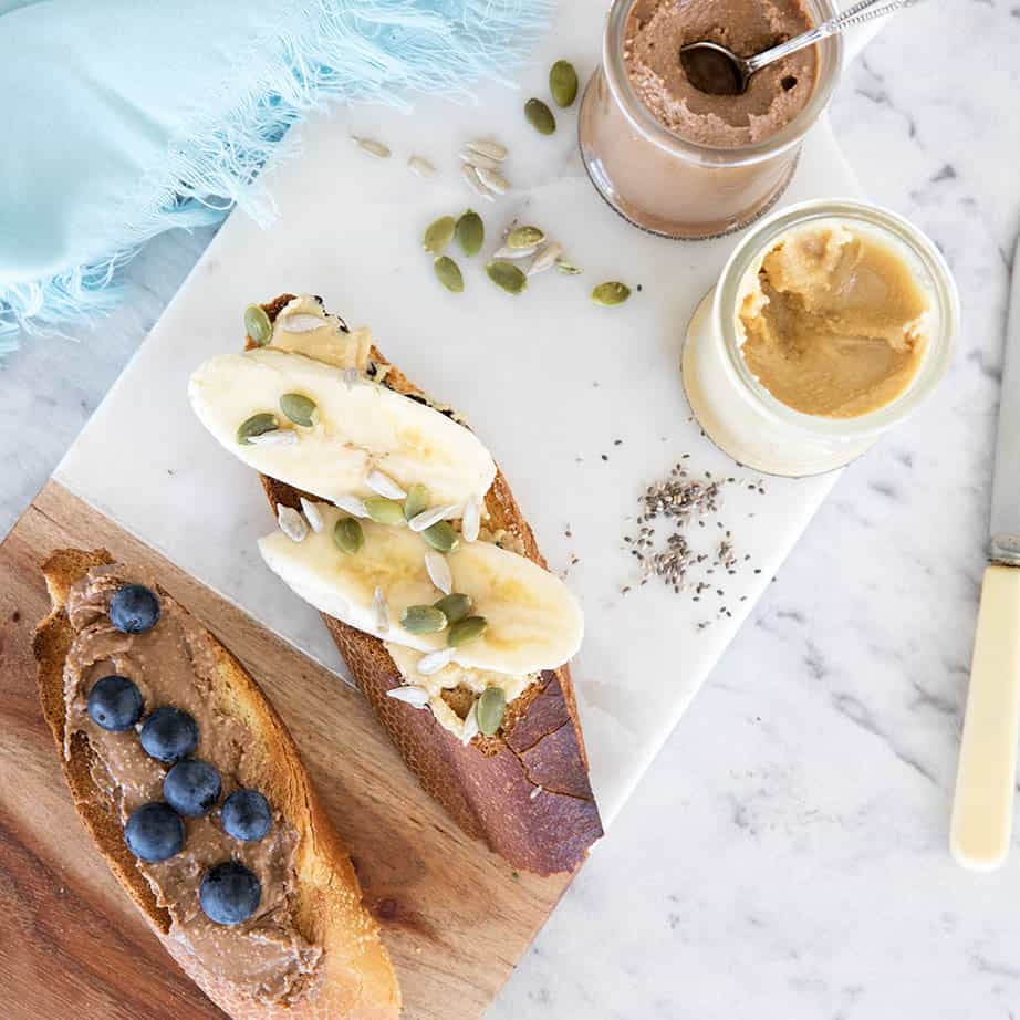 Over head shot of toast with nut butters and fruit on a chopping board