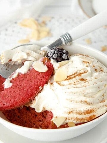 Close up of red velvet cake in a bowl with cream and nuts