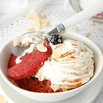 Close up of red velvet cake in a bowl with cream and nuts