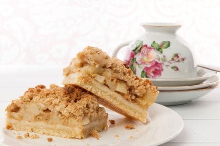 Apple Tart with Streusel topping on white background with floral tea cup
