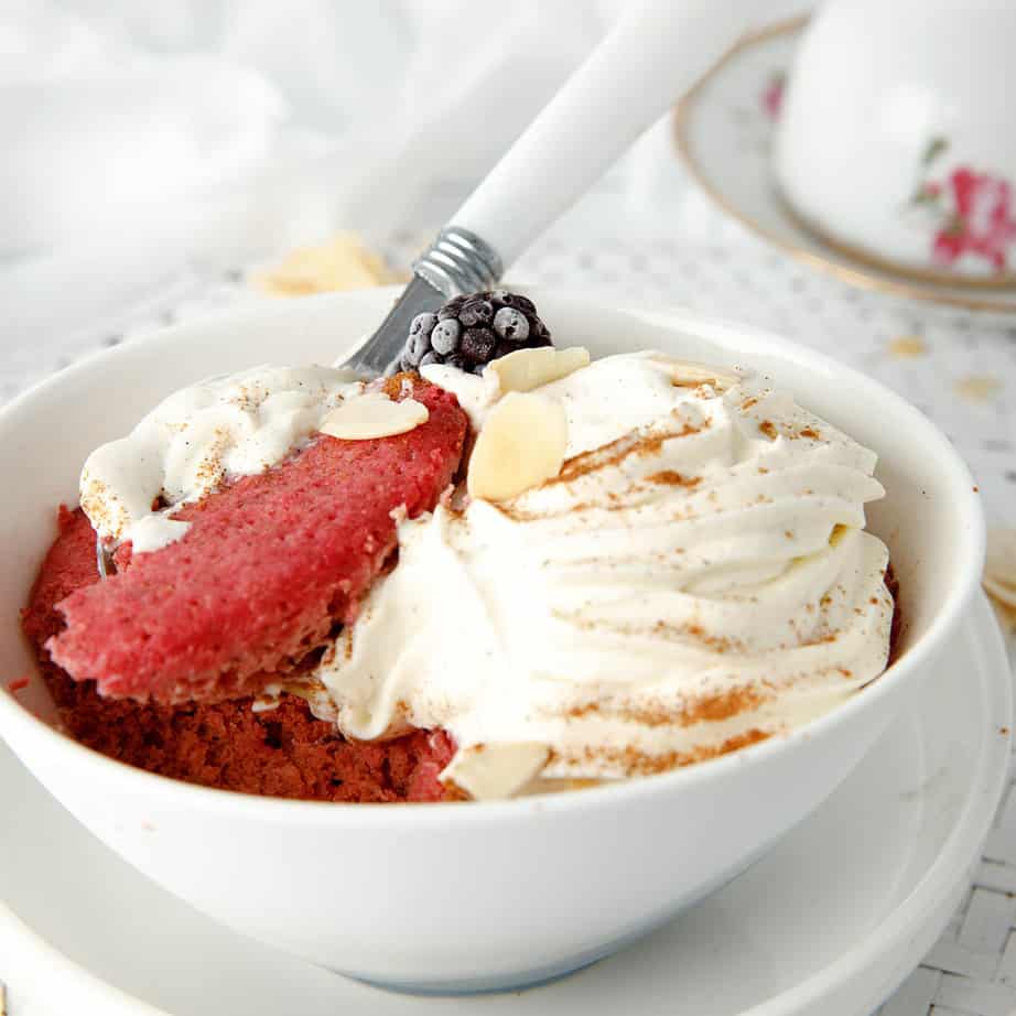 Keto Mug Cake in a bowl with cream and nuts