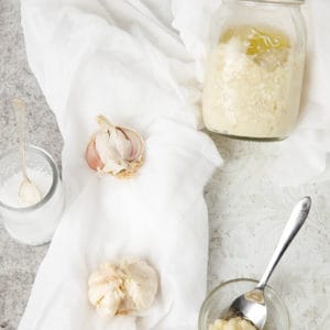Overhead shot of homemade garlic paste on a white background showing ingredients