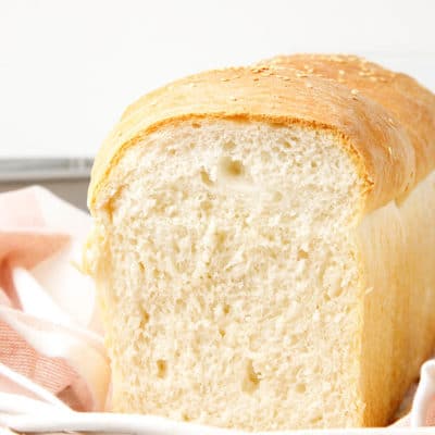 Sliced basic bread recipe loaf on a striped tea towel