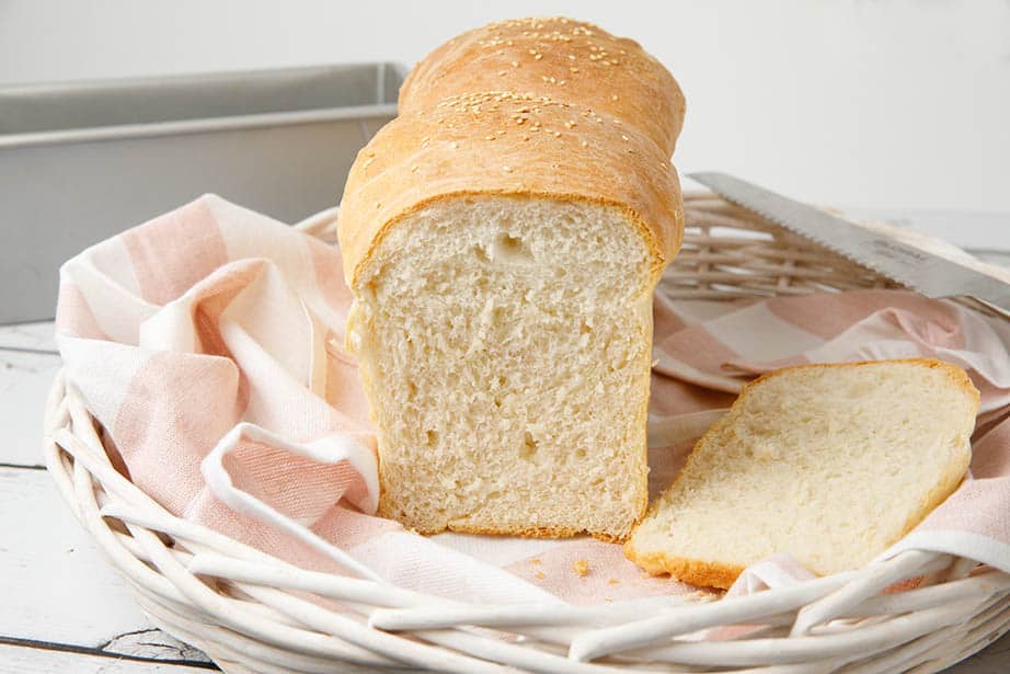 Fresh sliced basic bread recipe loaf on a striped tea towel