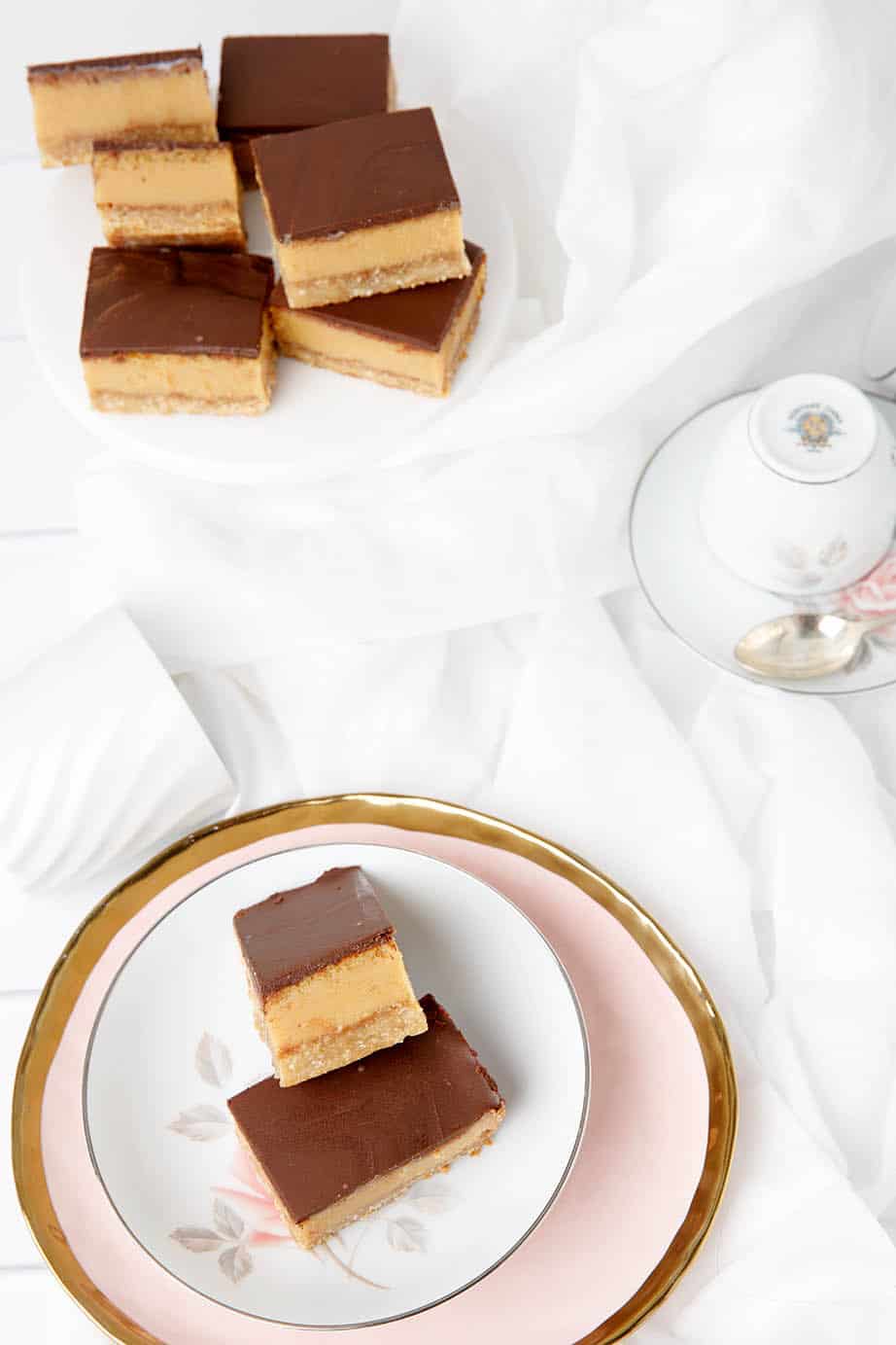 Overhead shot of caramel slice on a white background, pink plate