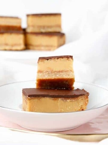 multiple caramel slices on a white and pink plate, light background