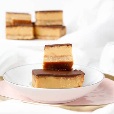 multiple caramel slices on a white and pink plate, light background