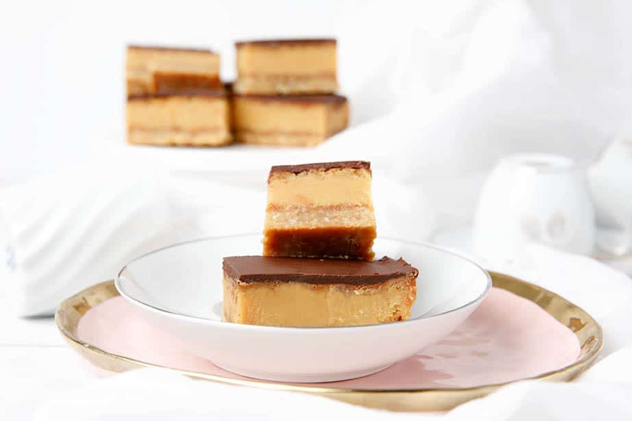 multiple caramel slices on a white and pink plate, light background