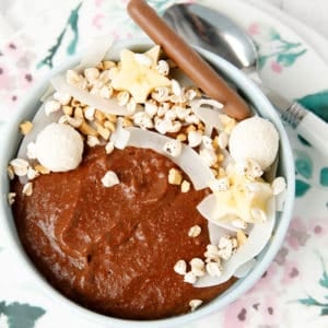 Chocolate porridge in a bowl with decorative topping like cocnut, peanuts bliss balls and banana