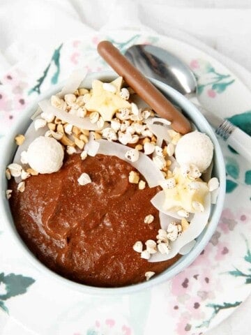 Chocolate porridge in a bowl with decorative topping like cocnut, peanuts bliss balls and banana
