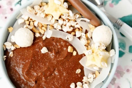Chocolate porridge in a bowl with decorative topping like cocnut, peanuts bliss balls and banana