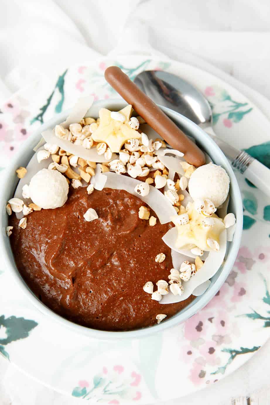 Chocolate porridge in a bowl with decorative topping like cocnut, peanuts bliss balls and banana