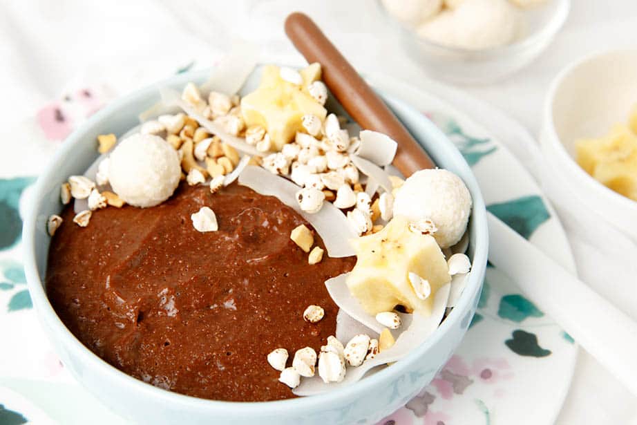 Landscape image of chocolate porridge with toppings on the side