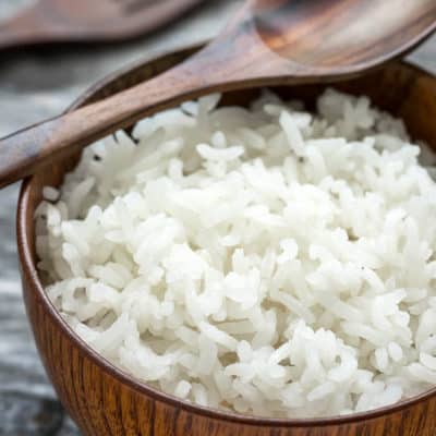 White sticky rice in a wooden bowl grey background