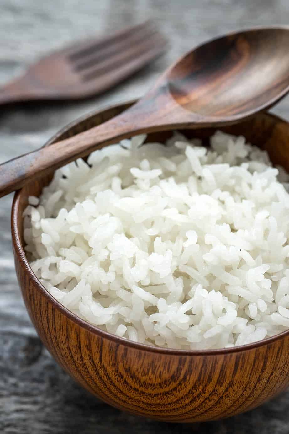 White sticky rice in a wooden bowl grey background