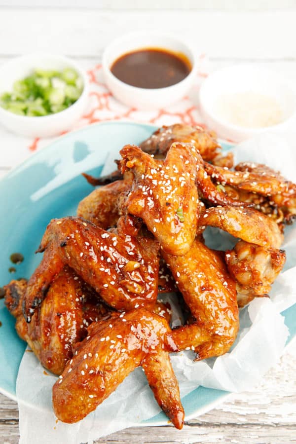 Sticky Korean wings on a plate with condiments