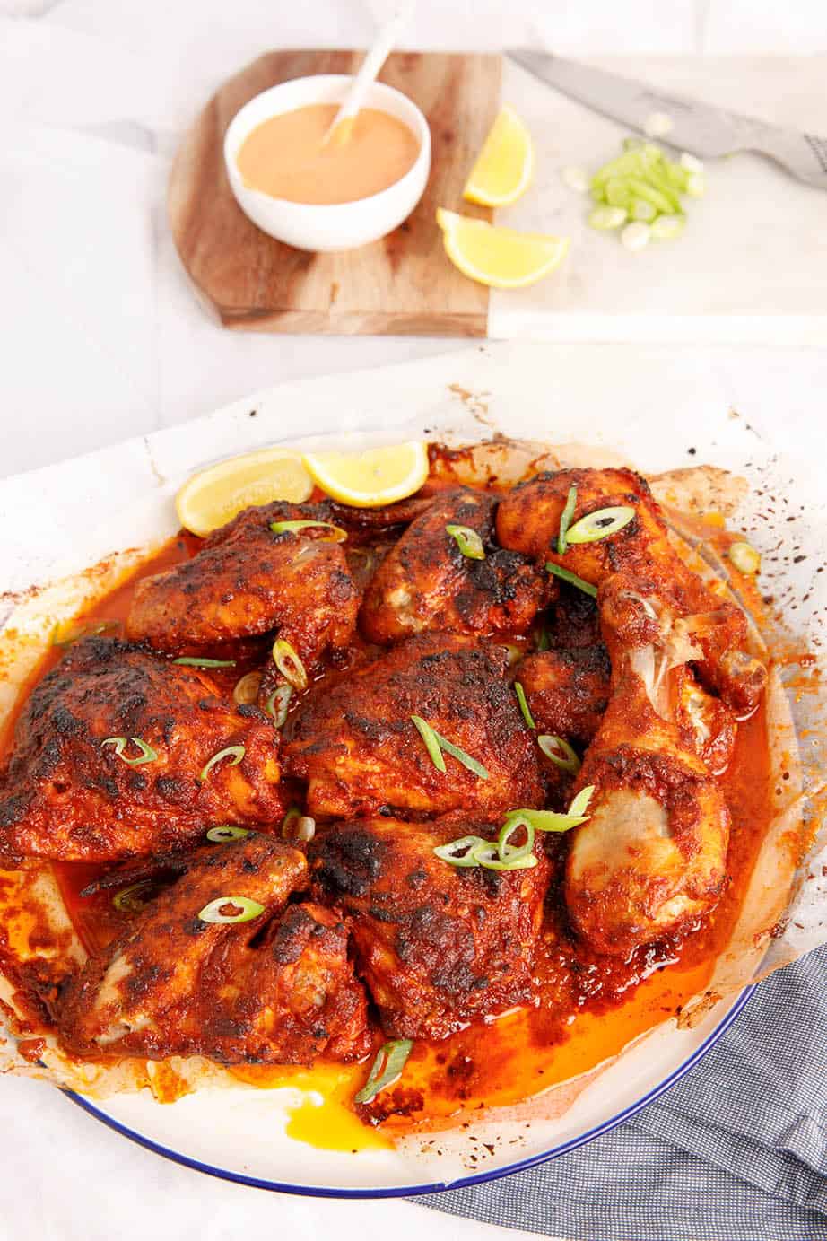 Peri Peri Chicken on a white background with lemon and aioli in the background