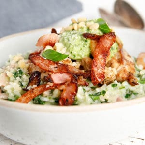 Close up chicken risotto with bacon and pesto topping on white background