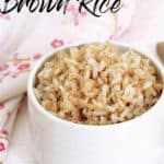 Titled pinterest image Cooked brown rice in a white bowl wooden spoon and floral serviette