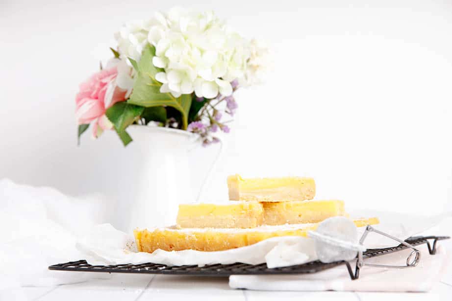 Landscape image of lemon slice cut into bars on a cooling rack.