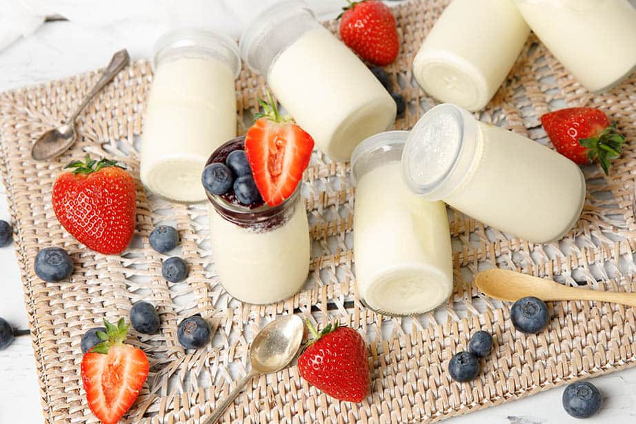 Landscape image yoghurt pots on a placemat with fruit