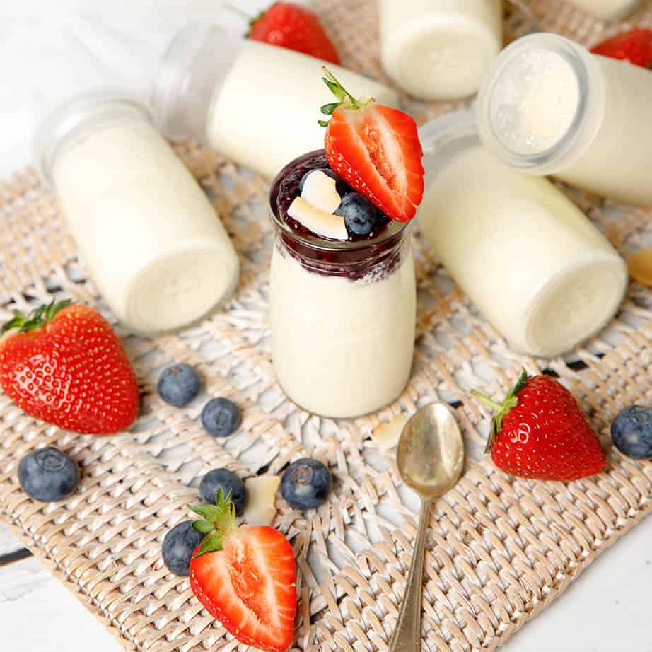 Glass yoghurt pots on a background with strawberries and blueberries