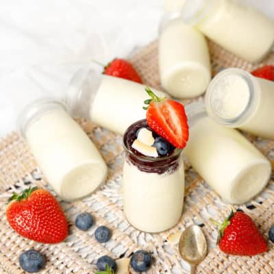 Glass yoghurt pots on a background with strawberries and blueberries