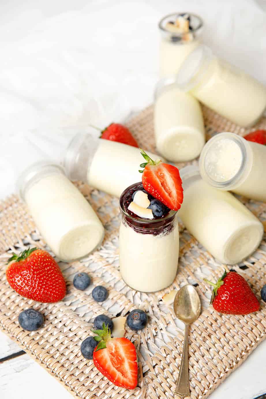 Glass yoghurt pots on a background with strawberries and blueberries