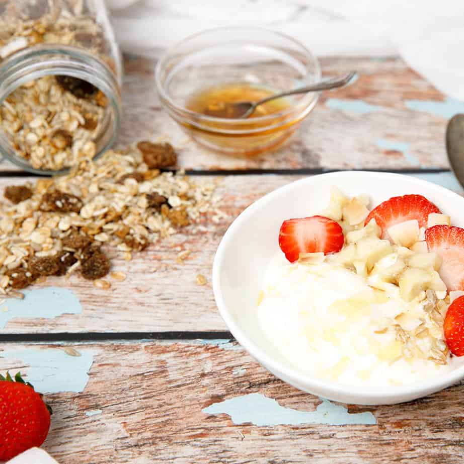 Yoghurt and muesli on a wooden table with fruit