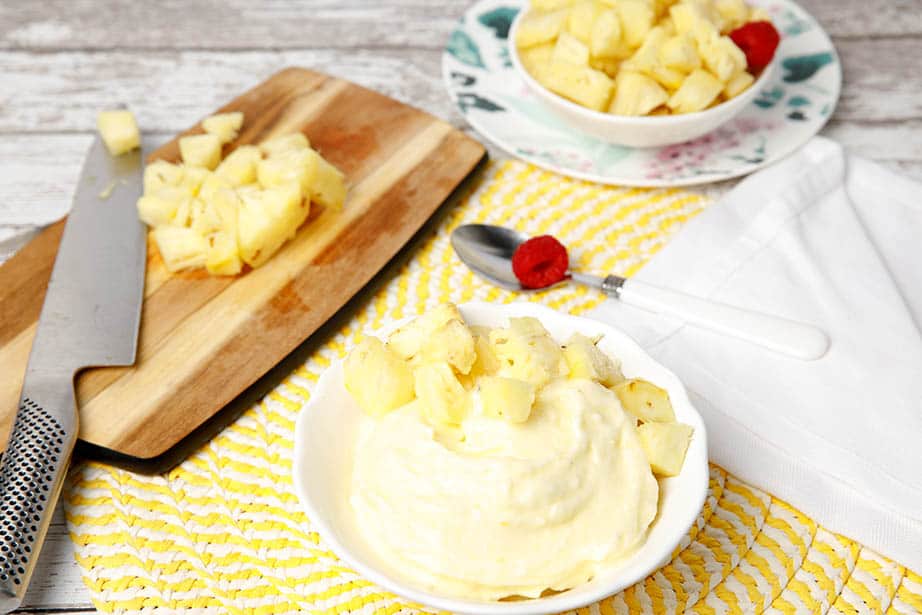 Landscape image pineapple softserve dessert in a white bowl with chopped pineapple