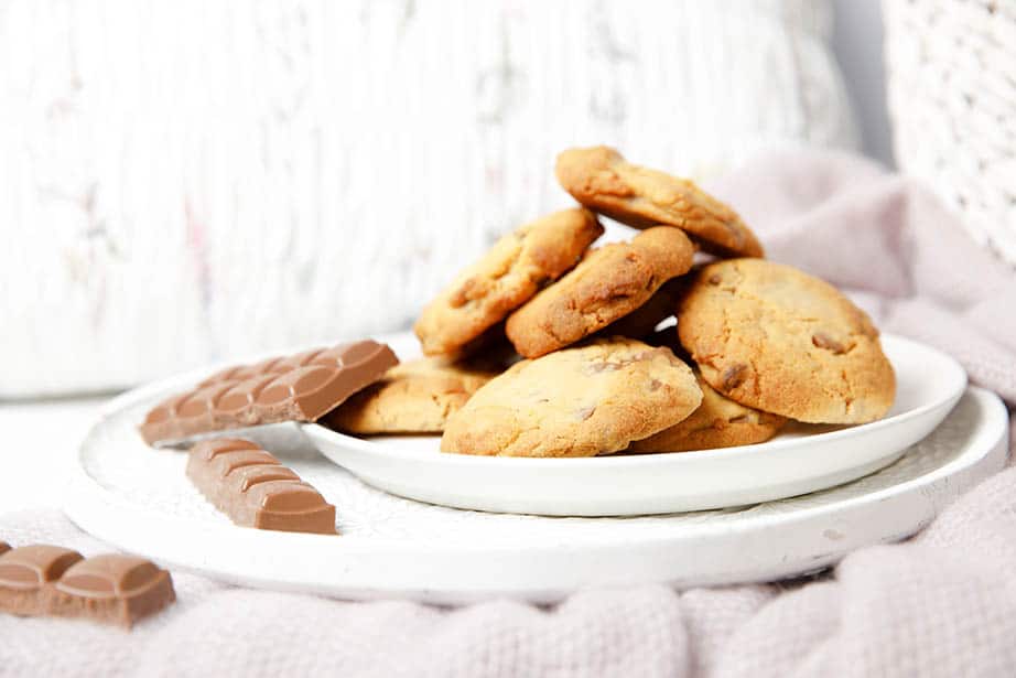 A plate of chocolate chip cookies on a pink blanket