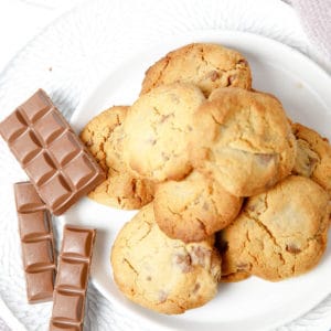 Overhead pic of choc chip cookies on a plate on pink blanket