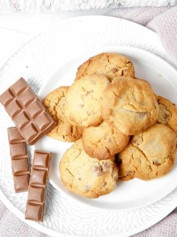 Overhead pic of choc chip cookies on a plate on pink blanket