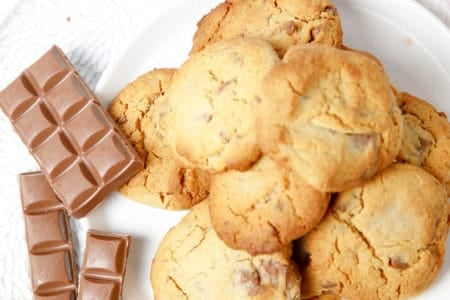Overhead pic of choc chip cookies on a plate on pink blanket
