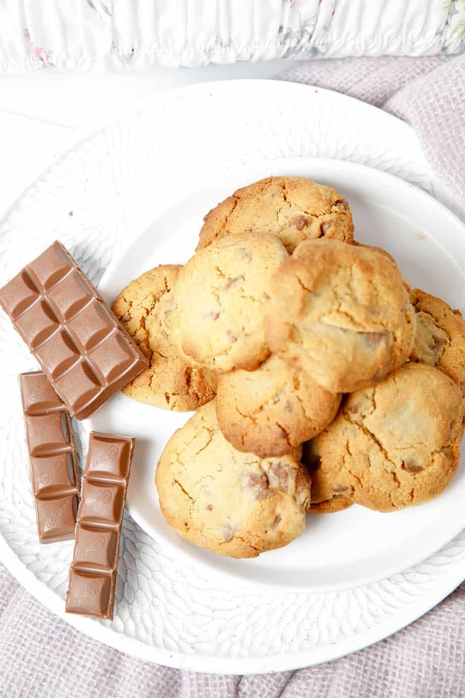 Overhead pic of choc chip cookies on a plate on pink blanket