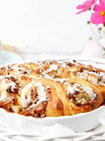 Cinnamon Scrolls in a white baking dish with pink flowers in the background