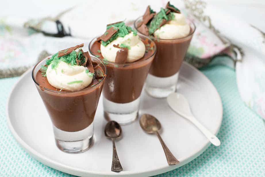 Three chocolate peppermint mousse desserts in a glass topped with cream