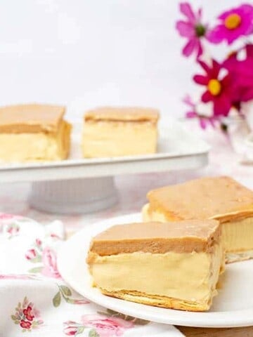 Landscape image of two Cadbury Caramilk Slices on a floral tablecloth